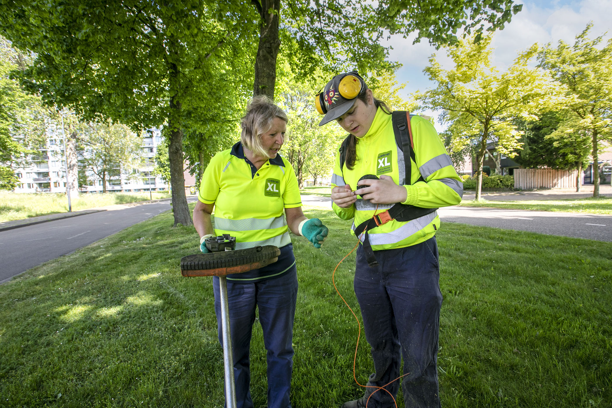 Op de foto staan twee collega's uit het Groen. Ze zijn bezig met het op de juiste manier aansluiten van apparatuur om het gras te maaien