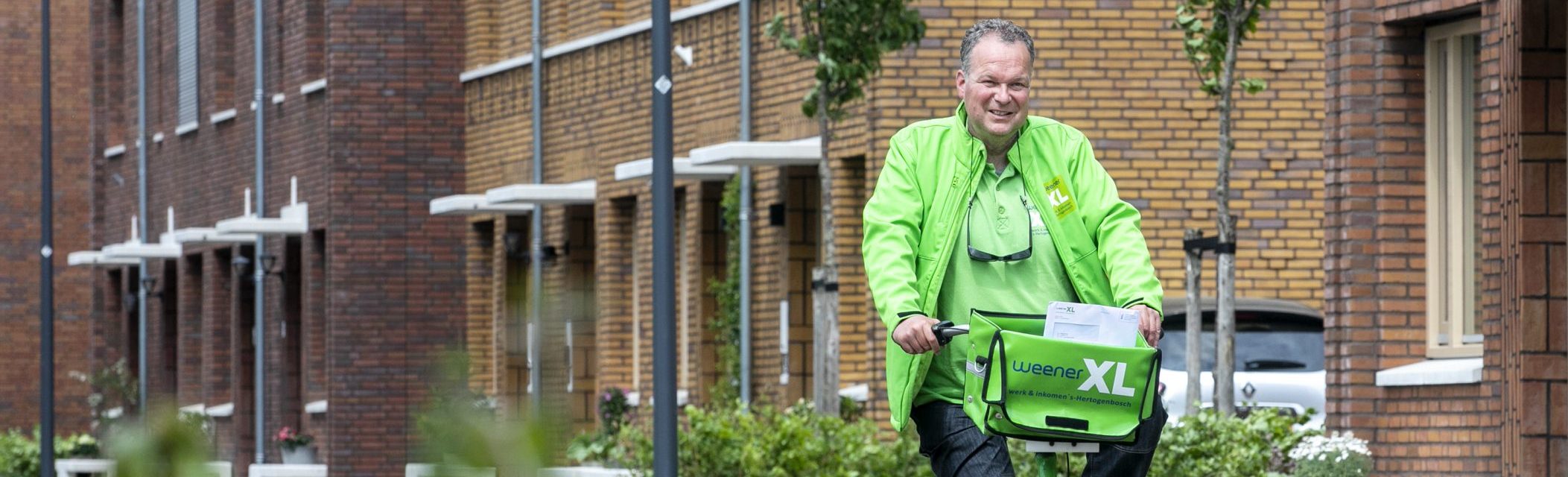 Op de foto staat een foto van collega Marcel van de Post. Hij fietst op een groene Weener XL fiets en in zijn fietstas zitten poststukken