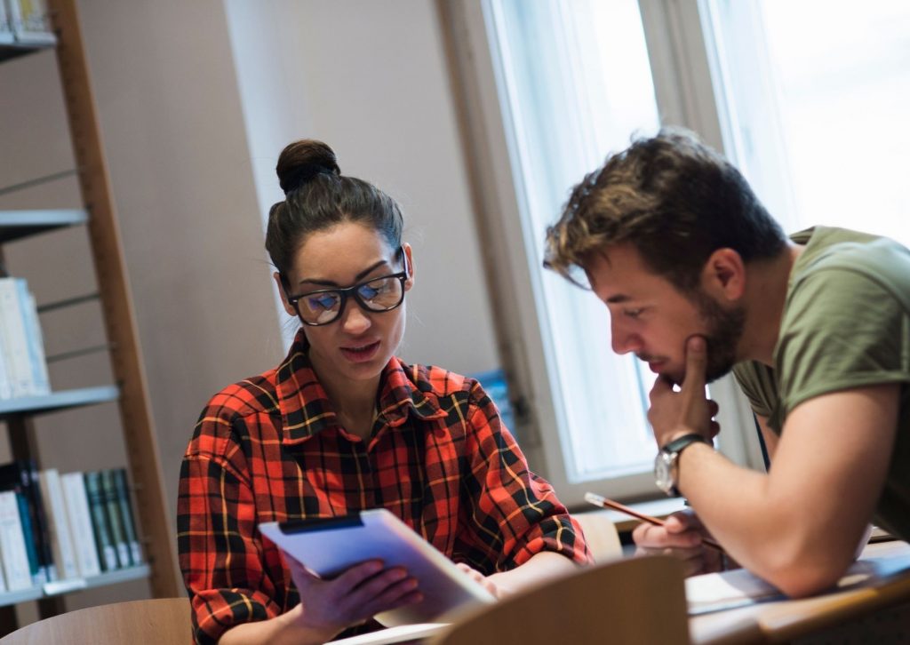 Student kijkt bij andere student op de tablet 