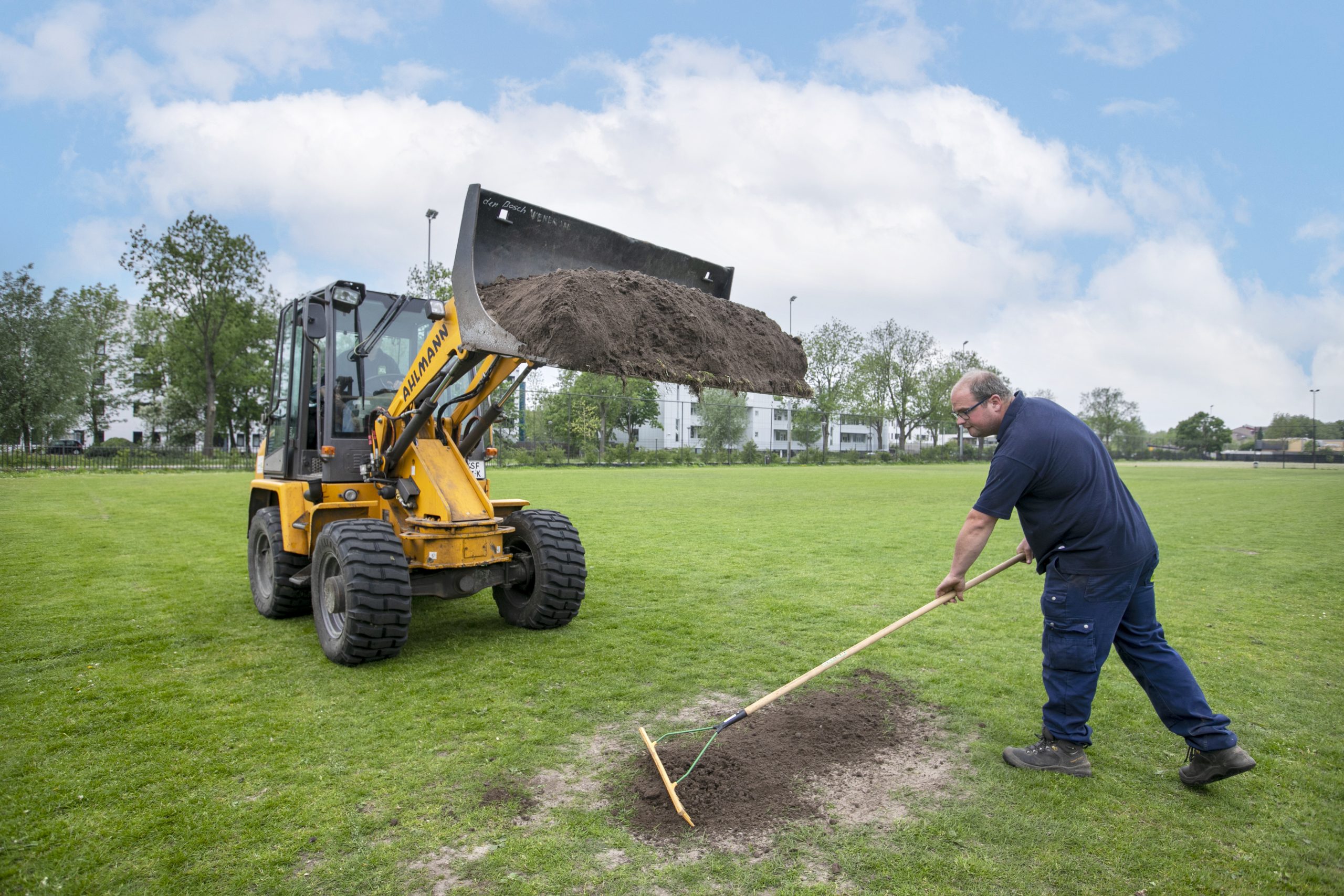 Collega van de afdeling Groen harkt veld