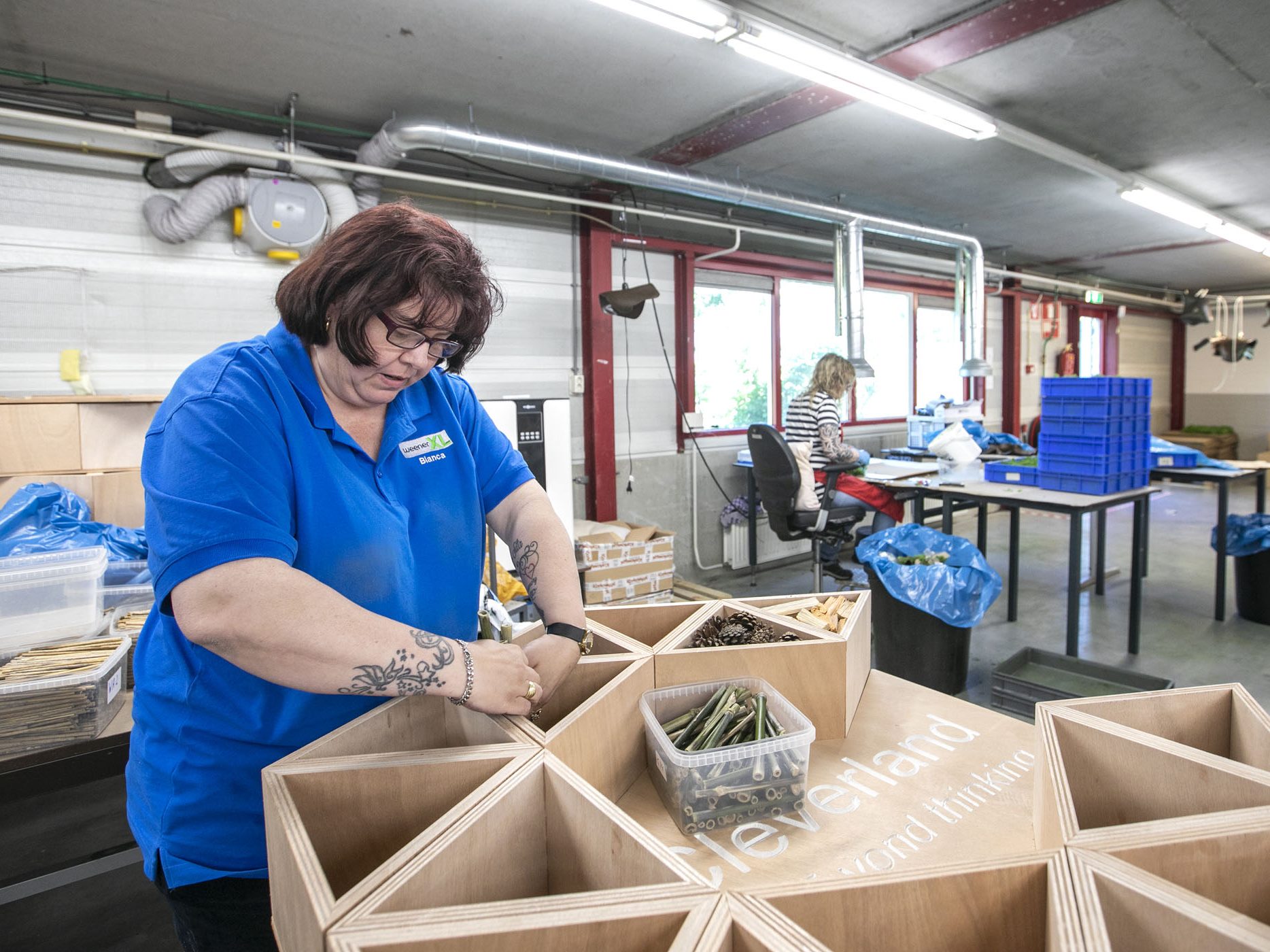 Een collega van de afdeling Social Sofa is bezig met het sorteren van materialen. Ze draagt een blauwe polo