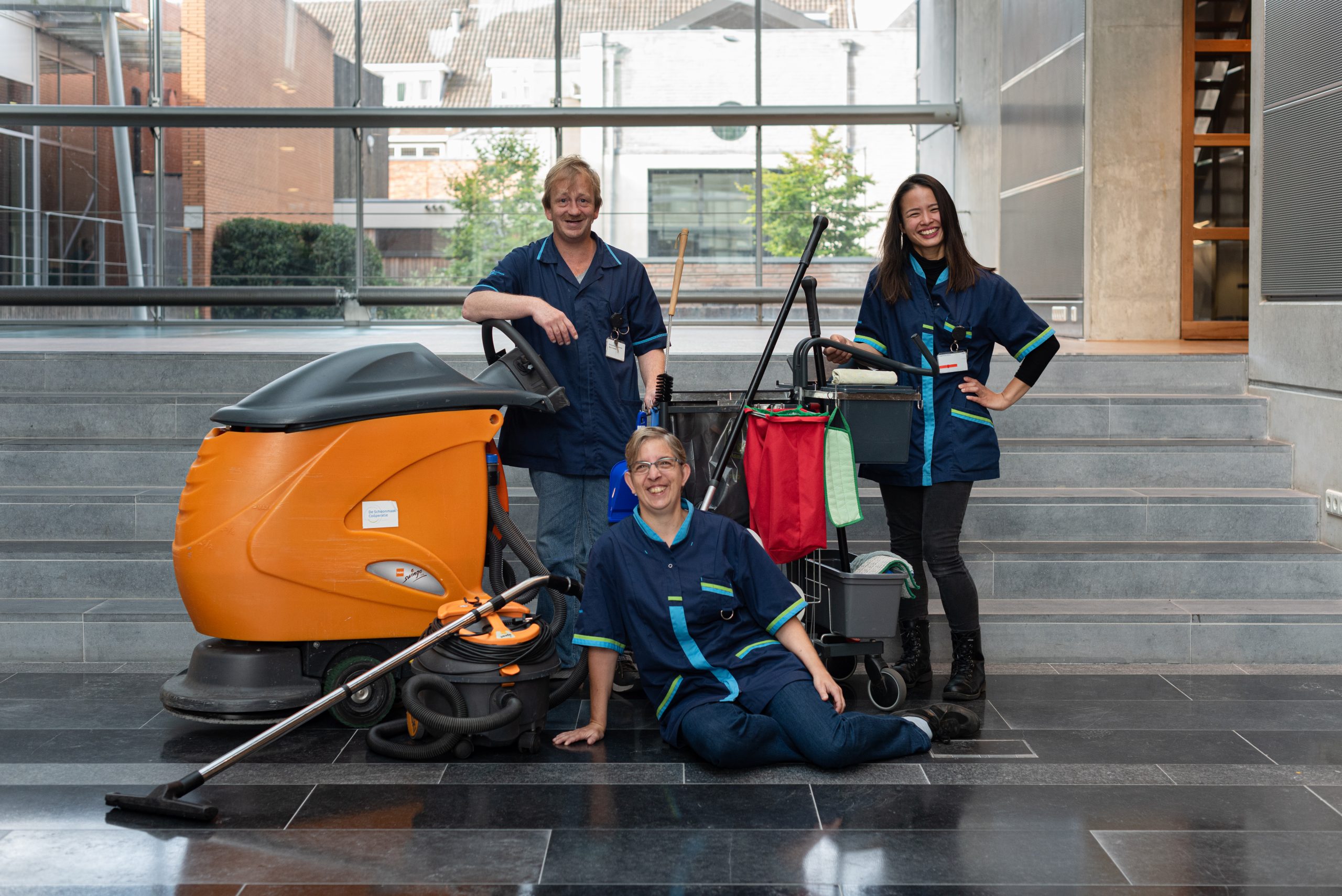 Collega's van De Schoonmaak Coöperatie poseren bij een schoonmaakmachine