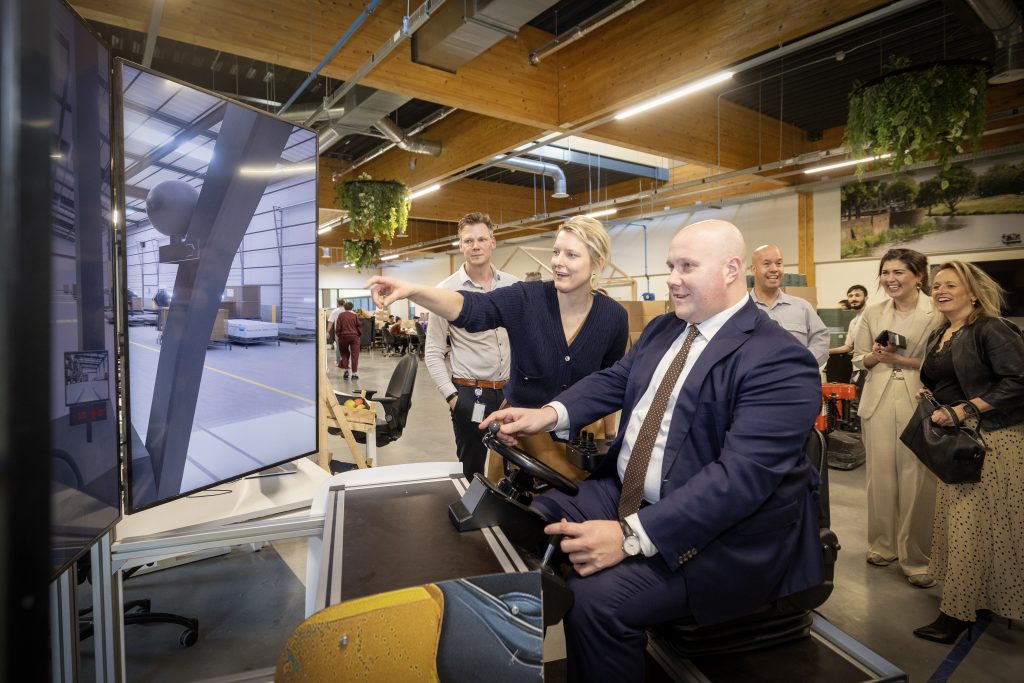 Minister Aartsen probeert de heftrucksimulator met de wethouder op de achtergrond
