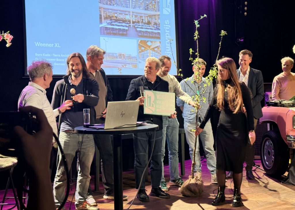 Prijsuitreiking met een aantal mensen op een podium die de prijs voor beste gebouw in ontvangst nemen